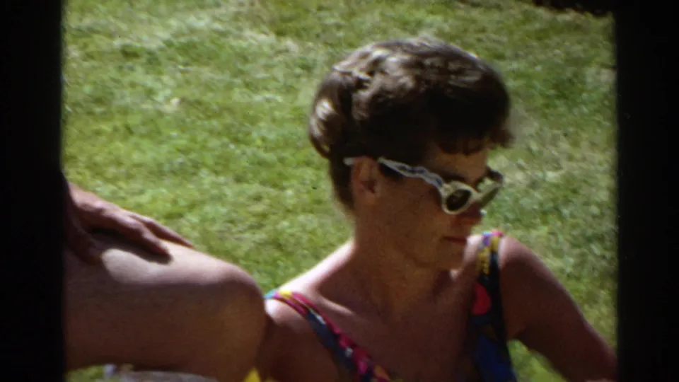Woman in white sunglasses sits on a grassy Scottsdale lawn during a 1968 outdoor card-playing scene.