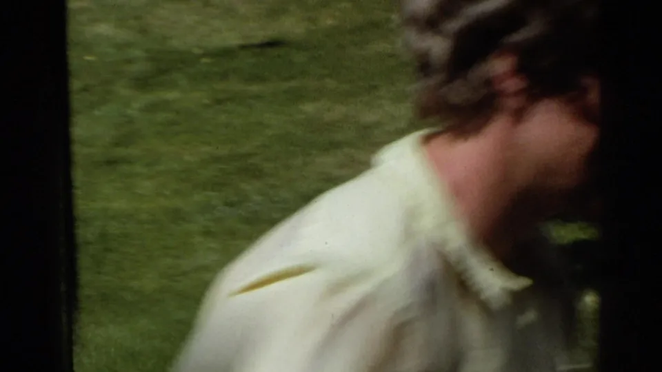 1968 Scottsdale frame with a blurred adult in a pale yellow shirt moving across the foreground against a green lawn.