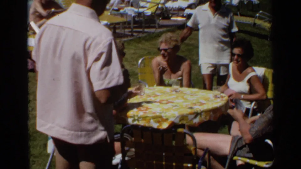 Adults at a Scottsdale outdoor table appear to converse while a man in a light shirt stands beside drinks and lawn chairs.
