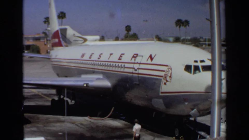 Side view of the Western Airlines aircraft at Scottsdale, Arizona, with red striping, cockpit windows, and palm trees visible.
