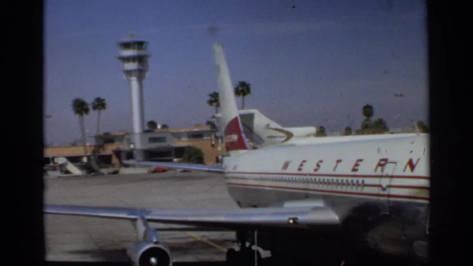 1968 Scottsdale airport view with a Western Airlines jet, control tower, tarmac, palm trees, and terminal structures.
