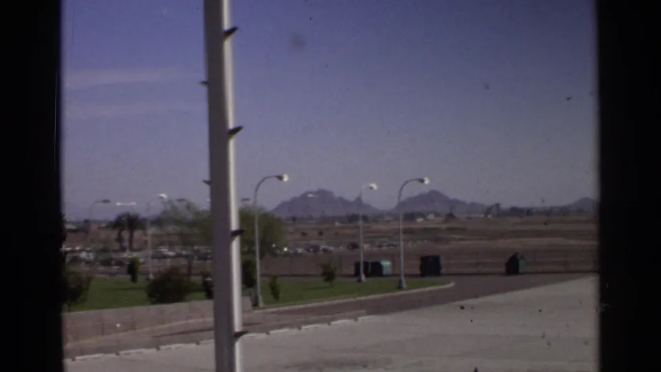 Scottsdale roadside view from 1968, showing light poles, open desert land, parked cars, and distant mountains.