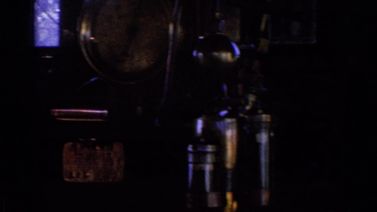 Dark train cab panel with gauges, levers, and a small bright window.