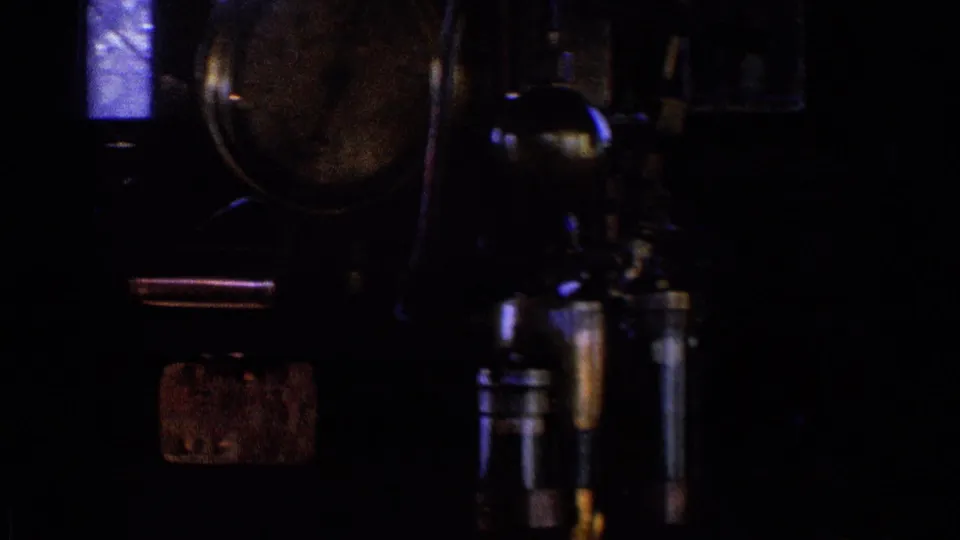 Dark interior train-control area in the Chicago 1976 clip, with analog gauges, metal levers, and a small window visible in grainy 8mm footage.
