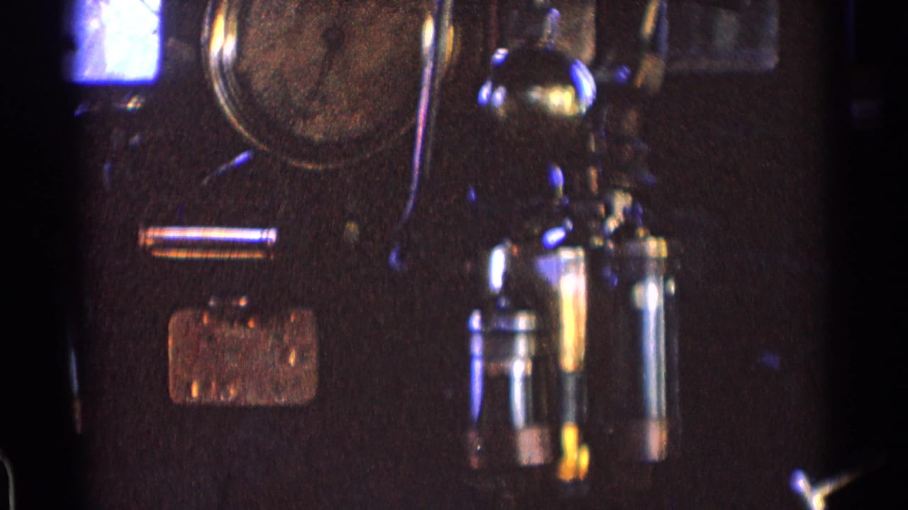 Closer view of a dark control panel with round gauge and paired metal handles.