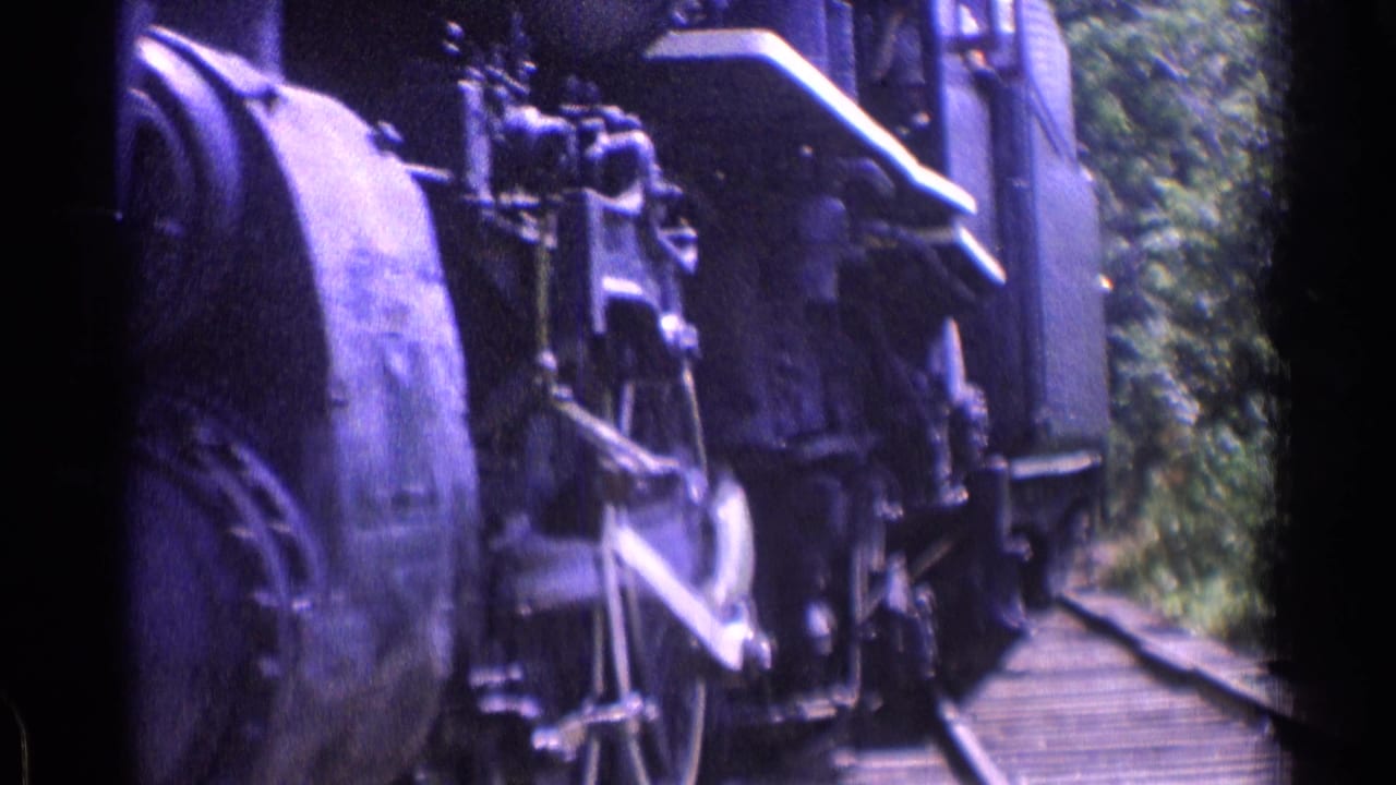 Close 1976 8mm view of a steam locomotive undercarriage moving along tracks in the Chicago-area metadata context.