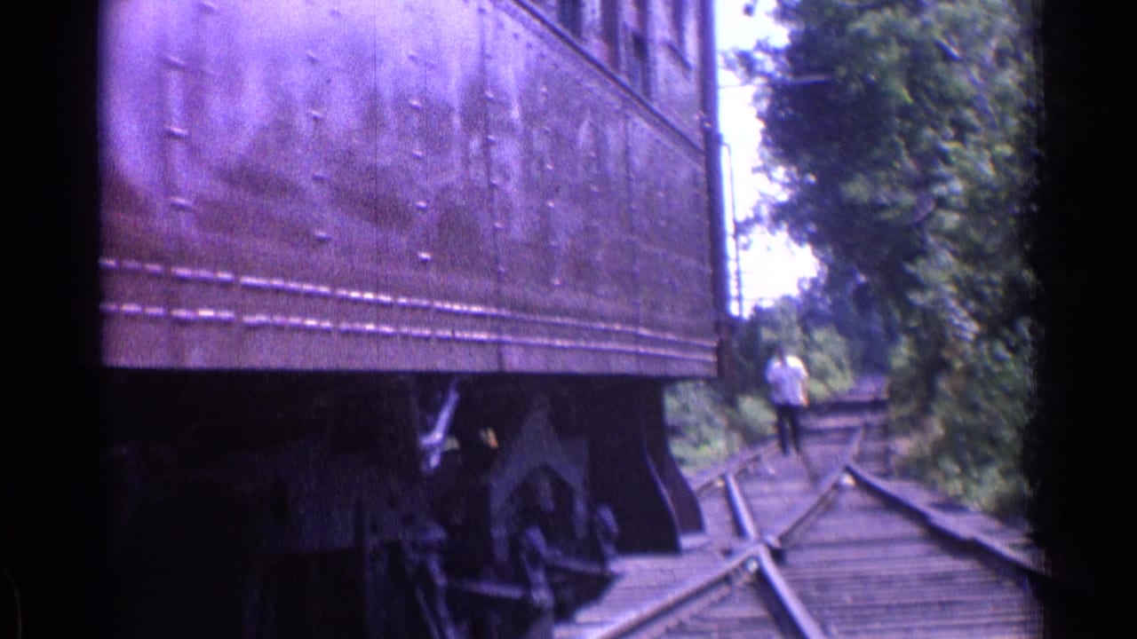 Rail car beside track switches with a person walking in the distance.
