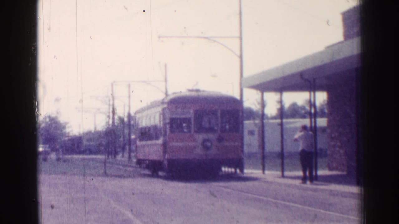 Transit car nears the shelter with a person standing nearby.