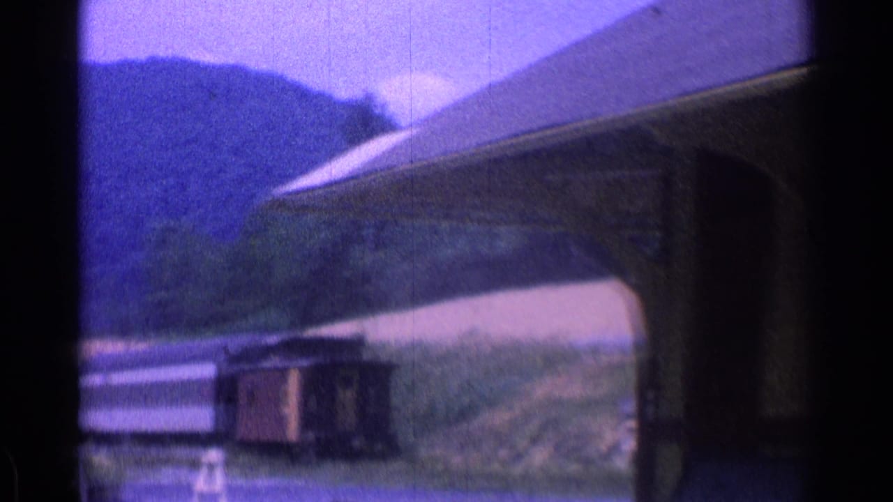 Rustic station roof and platform with mountains in the background.