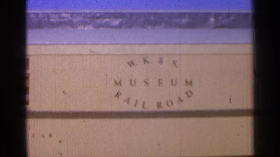 Close view of WK&S Museum Railroad lettering below a yellow train scene, with soft grain and color shift from 1976 8mm film.