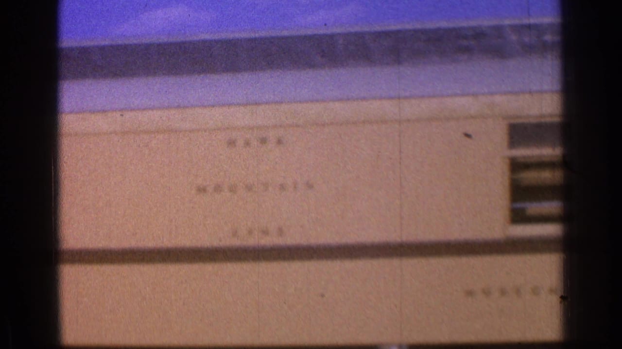 Circular railroad museum sign on a beige wall beneath a blue roof edge.