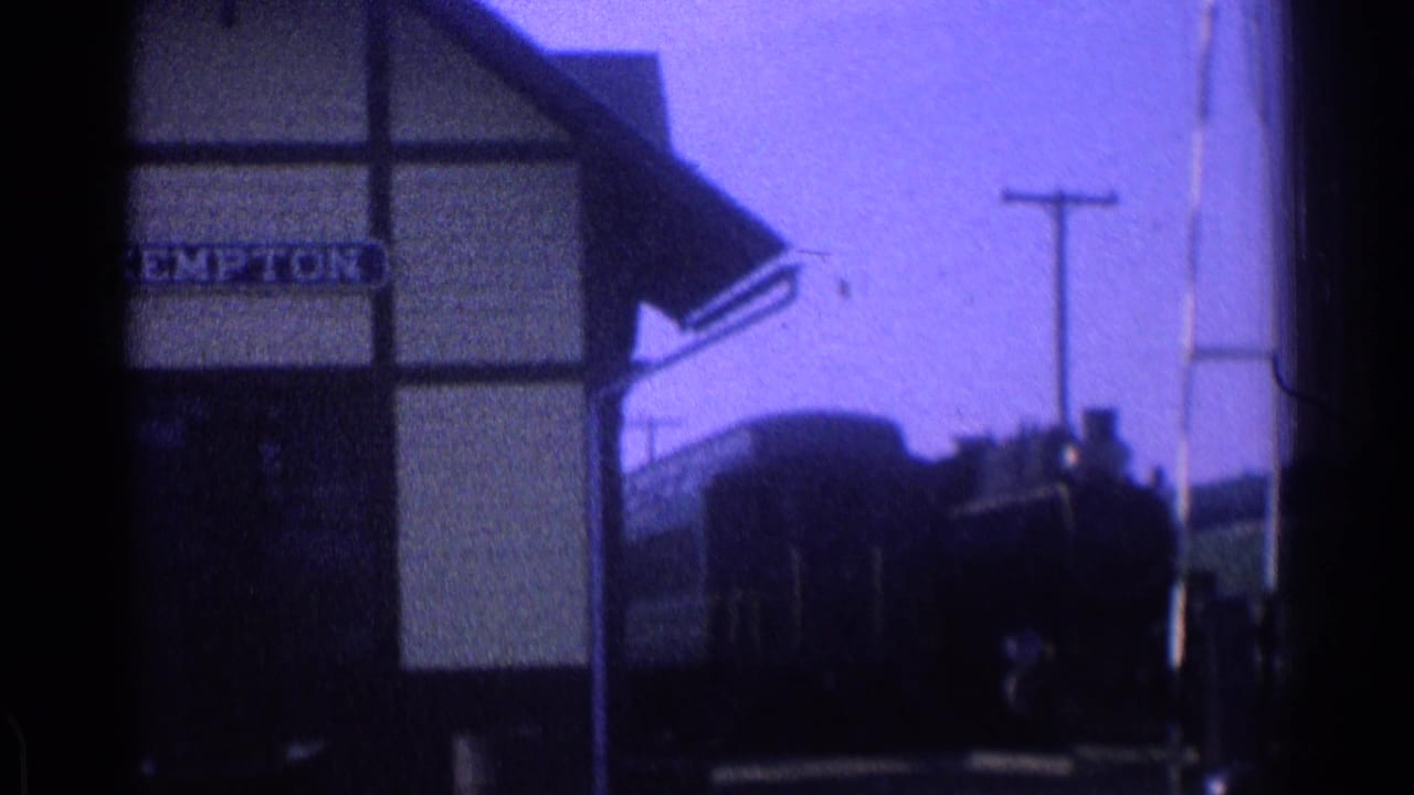 Station building with a clearer sign and a dark train or rail vehicle beside the platform.