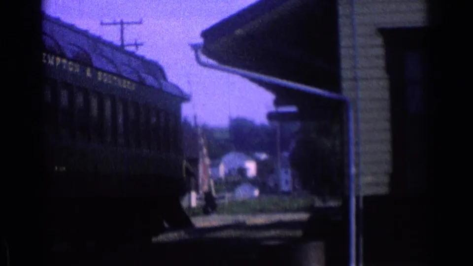 1976 8mm frame of dark green passenger rail cars near a station structure in the Chicago metadata context.