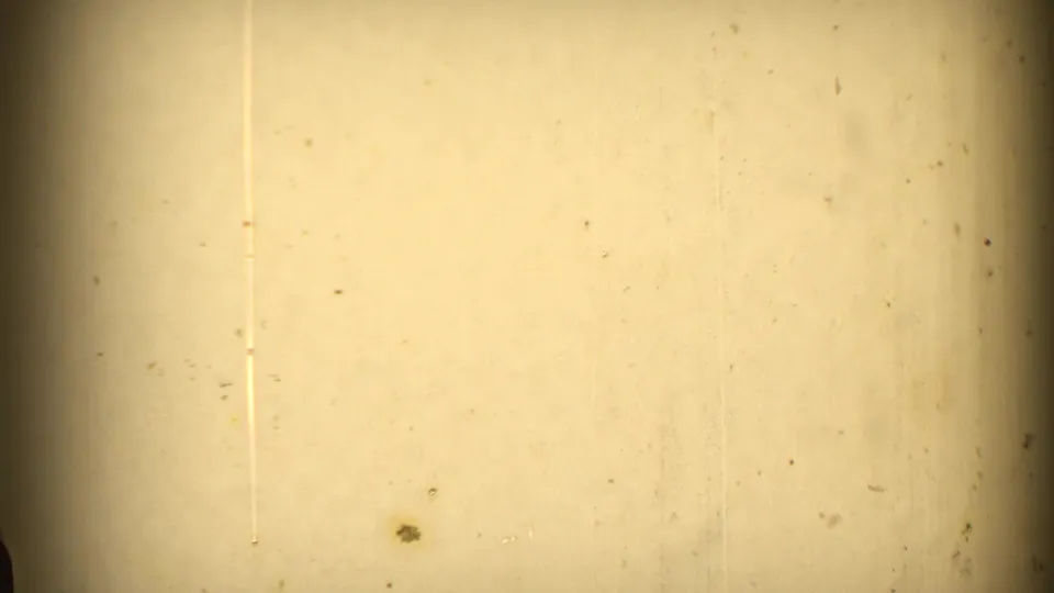 End frame or leader-like 8mm film with yellow exposure, visible dust, vertical marks, and dark vignetted edges.
