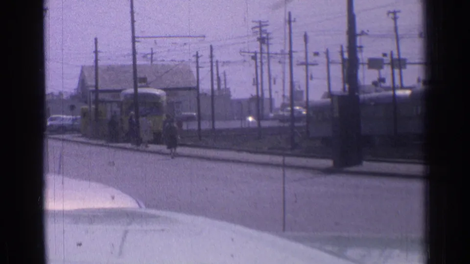 The yellow transit vehicle is farther left in frame as pedestrians stand or walk near the curb on a 1976 Chicago street.