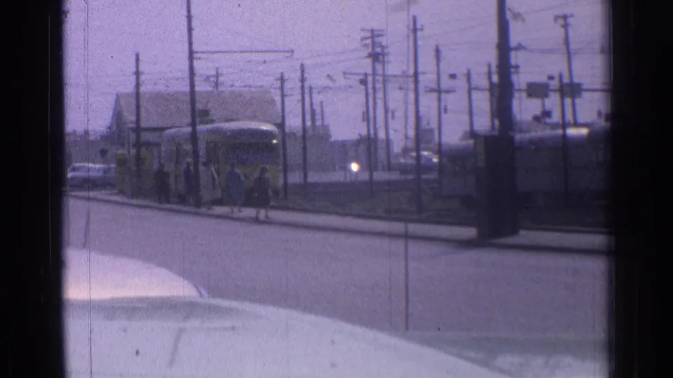 A yellow transit vehicle and pedestrians remain visible on the Chicago street, framed through dark film edges and foreground vehicle hood.