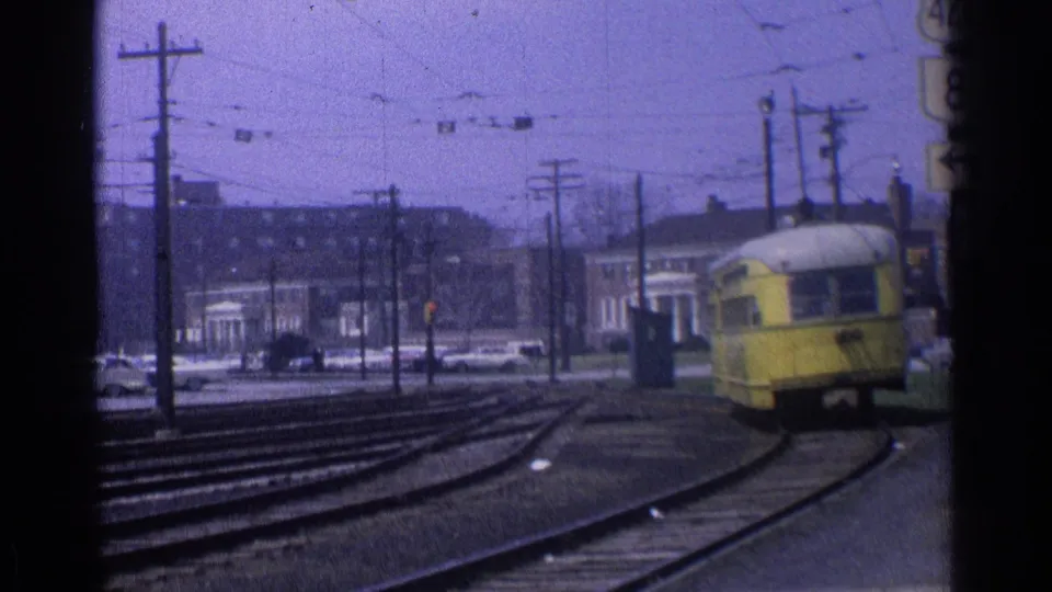 A wider 1976 Chicago view shows the yellow trolley farther down the curve amid rails, poles, wires, street signals, and low-rise buildings.