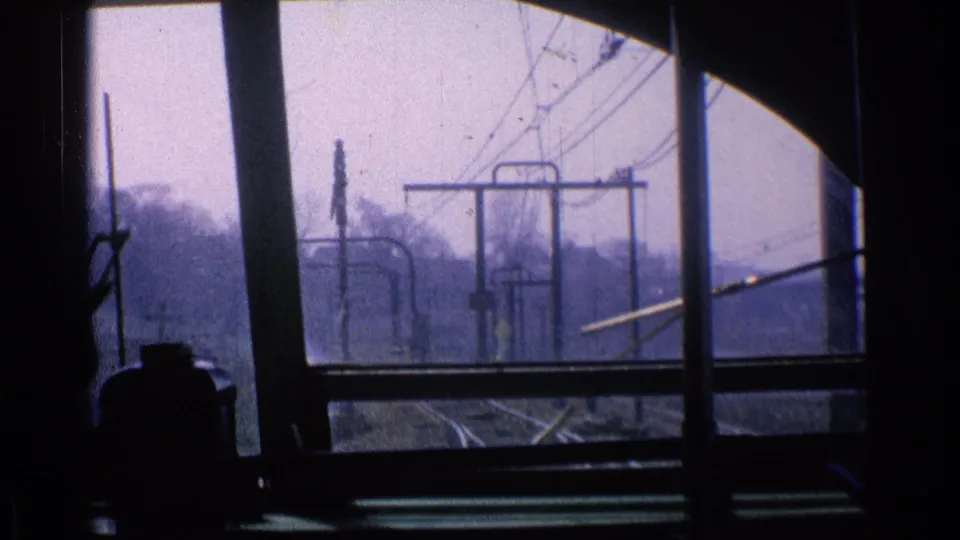 Chicago 1976 windshield view with utility poles, overhead electrical lines, roadside trees, and dark vehicle framing.