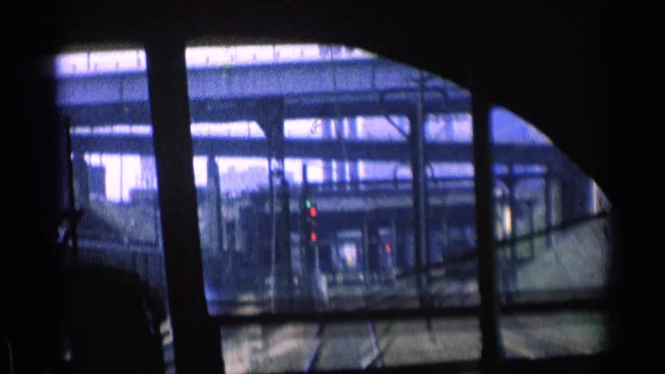 Chicago rail tracks, signal lights, and layered overhead structures appear through the shadowed train window in this 1976 home-movie frame.