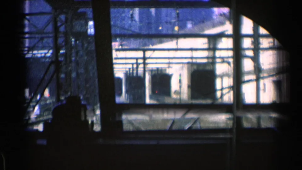 1976 Chicago transit view through a train window, showing tracks leading toward a bright tunnel-like opening under overhead framework.