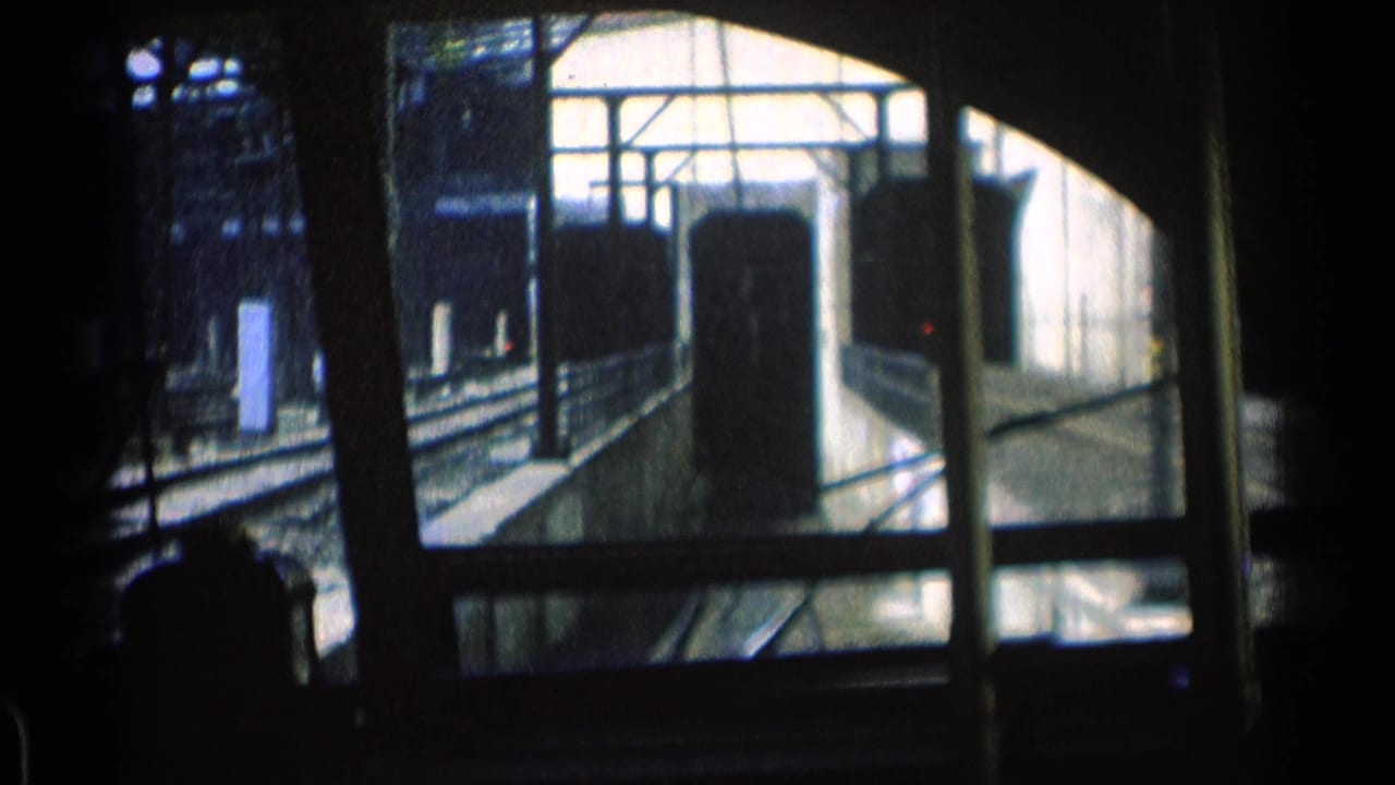 1976 Chicago transit footage viewed from inside a moving train, with tracks, platform edges, and window framing visible in low light.