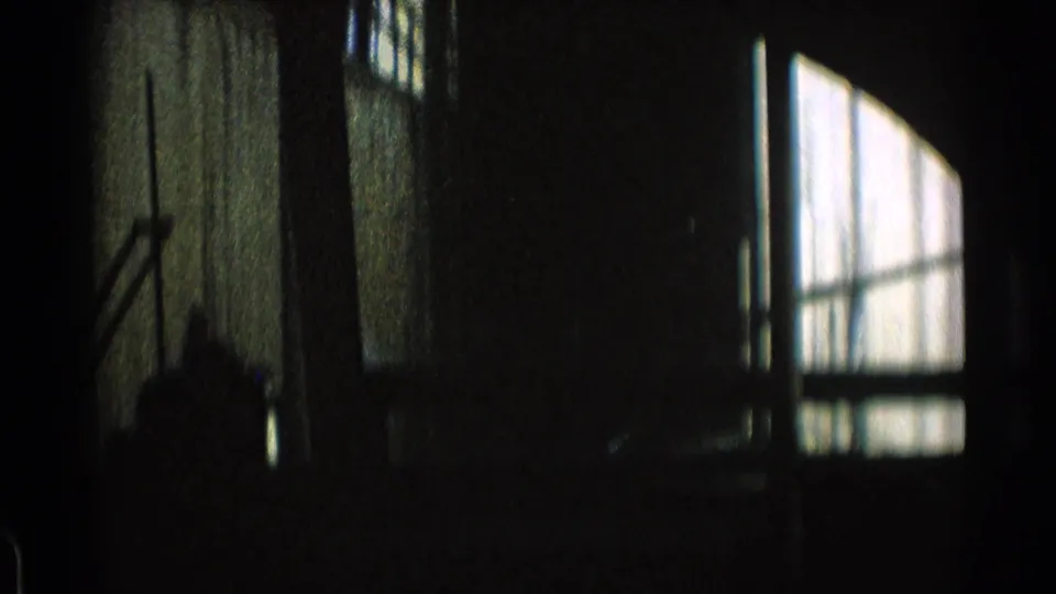 Dark, grainy train-window view in Chicago, with station glazing and interior reflections surrounding the moving frame.