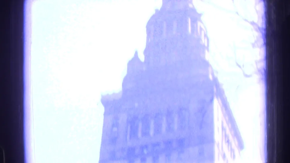 Blue-tinted final frame from the 1976 Chicago home movie, showing a tall building glimpsed through a window or opening after the transit shot.