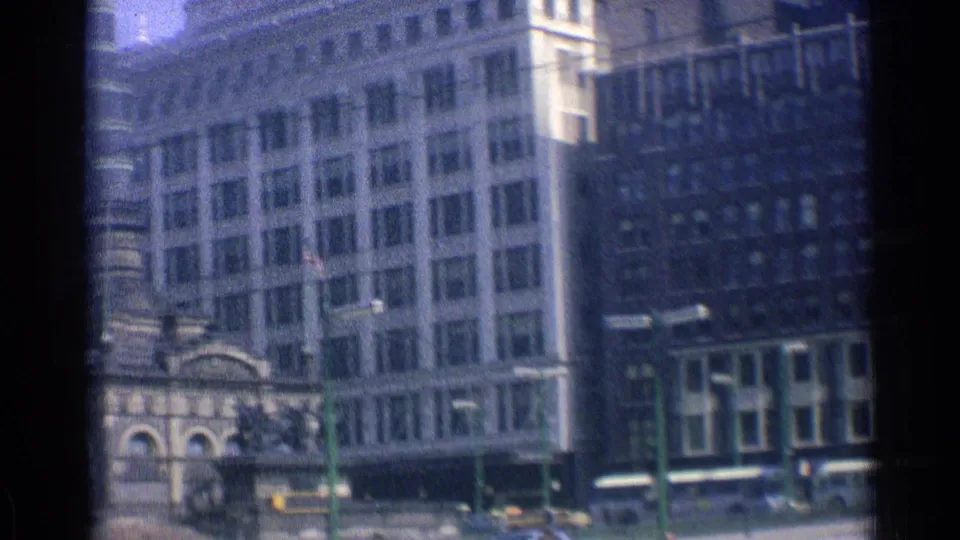 Downtown Chicago view with a prominent stone tower structure, surrounding office buildings, green poles, and street traffic.