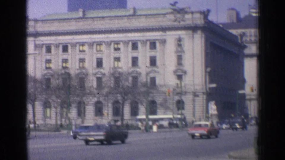 1976 Chicago street scene showing a classical-style civic building across a wide roadway, with cars, bare trees, traffic lights, and street activity.