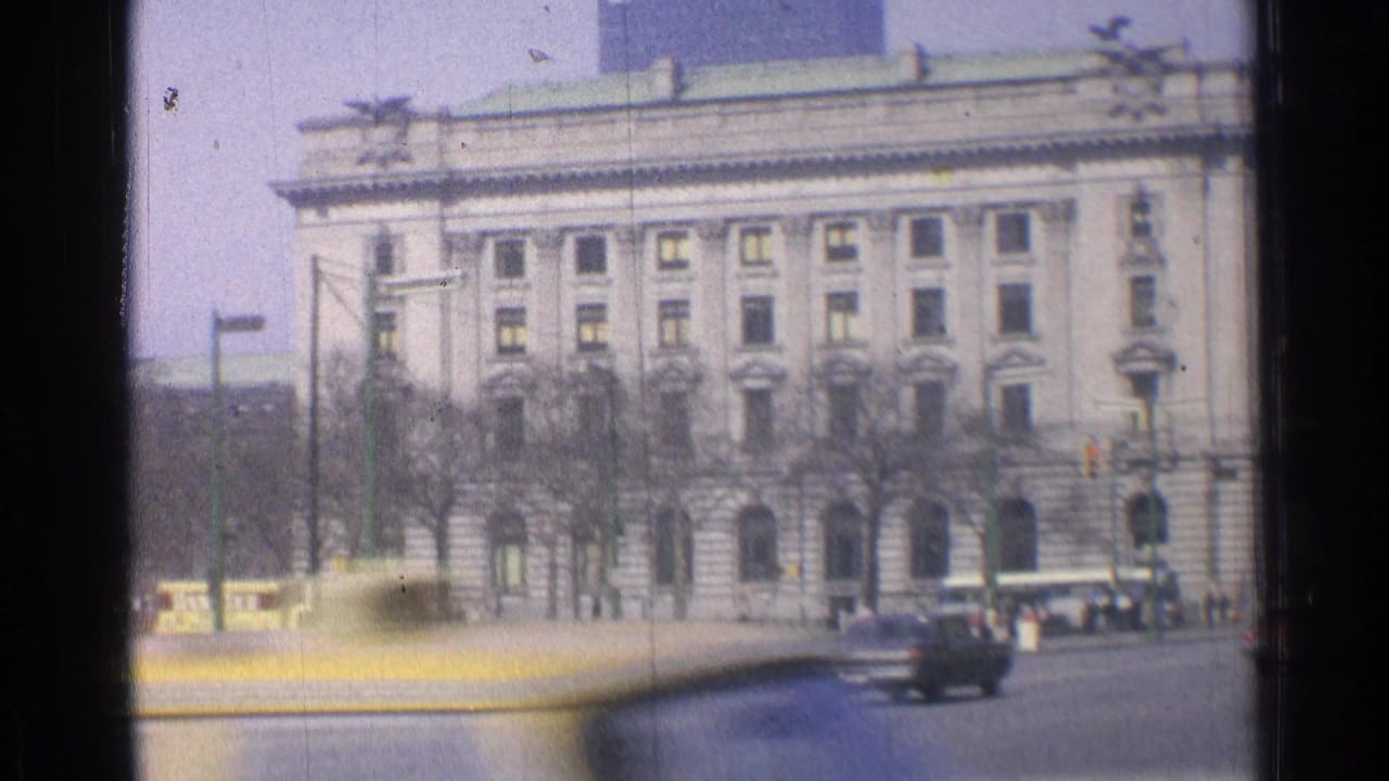 1976 Chicago street view with a large stone building, bare trees, traffic lights, and cars moving through an intersection.