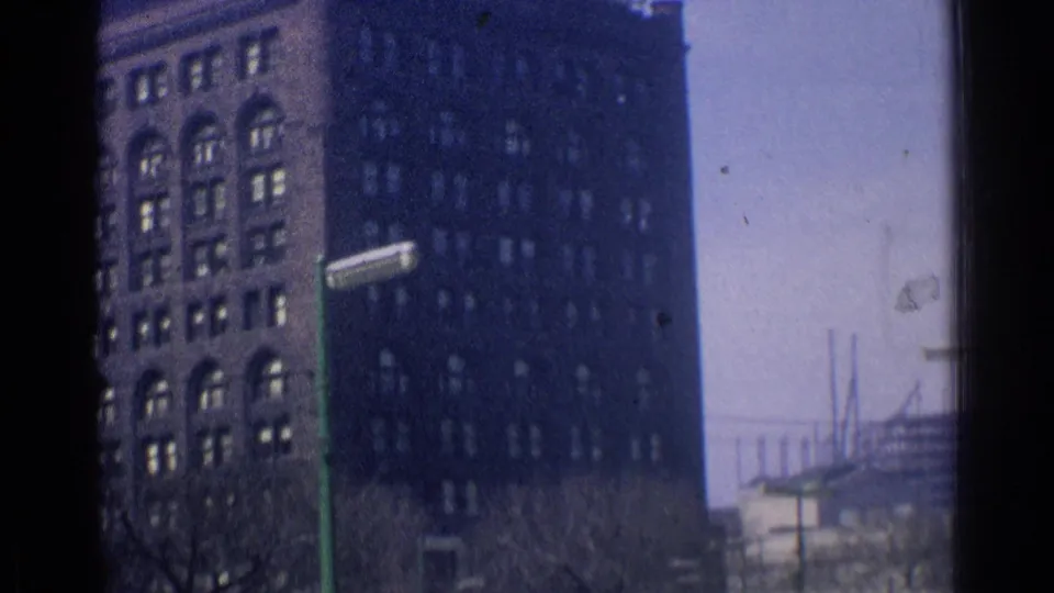Downtown Chicago view of a dark multi-story building, street fixtures, and a distant bridge or elevated structure at the edge of frame.