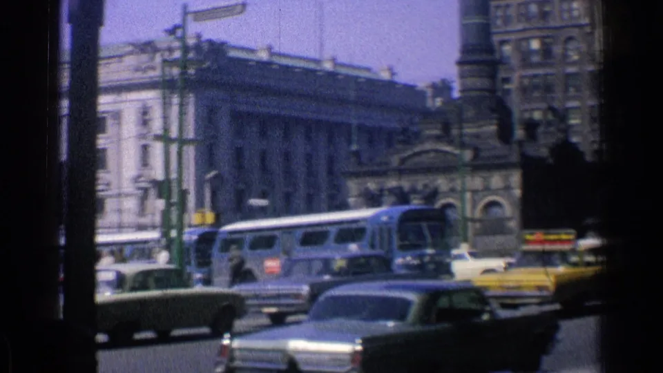1976 Chicago traffic view with a city bus, taxis, passenger cars, a pale facade, and older masonry buildings beyond the intersection.