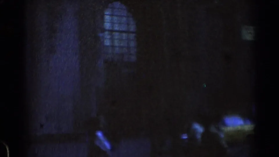 Dark opening frame from 1976 8mm Chicago rail footage, with a faint arched window shape and barely visible platform-side forms.
