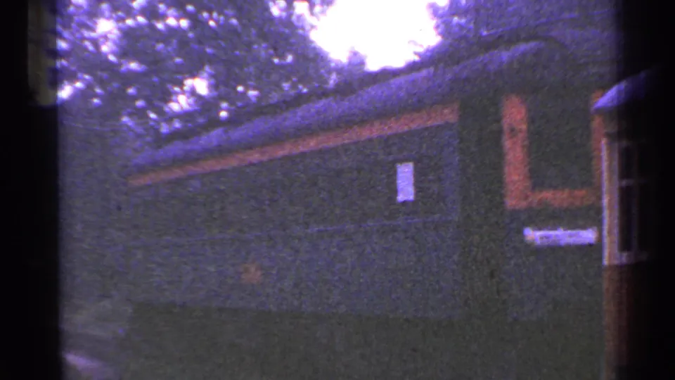 A darker side view shows rail or station structures with windows, trees, and soft handheld 8mm color.