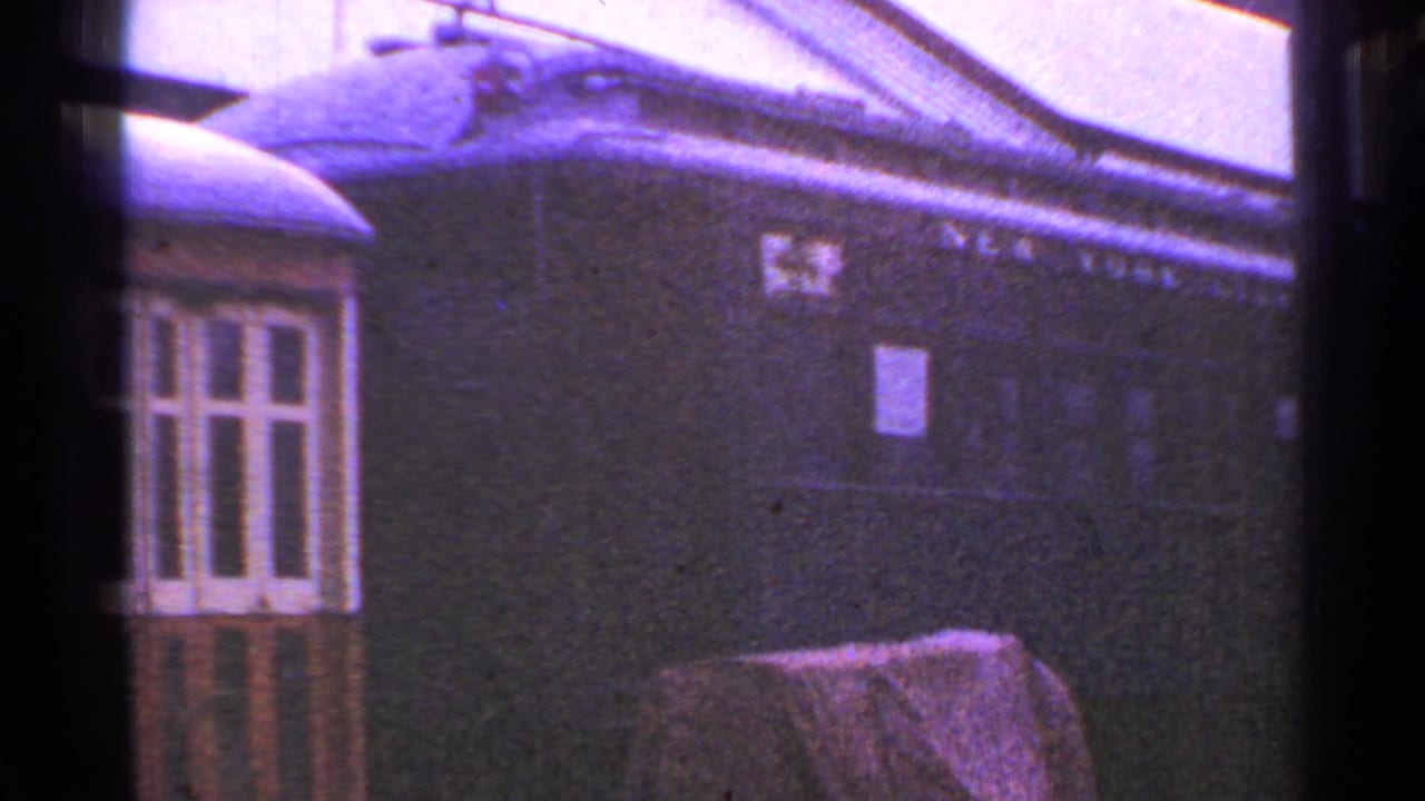 1953 Connecticut 8mm frame showing a dark, weathered passenger railcar with faded lettering and a nearby low structure.