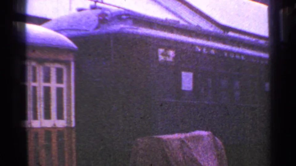 1953 Connecticut 8mm frame showing a dark, weathered passenger railcar with faded lettering and a nearby low structure.