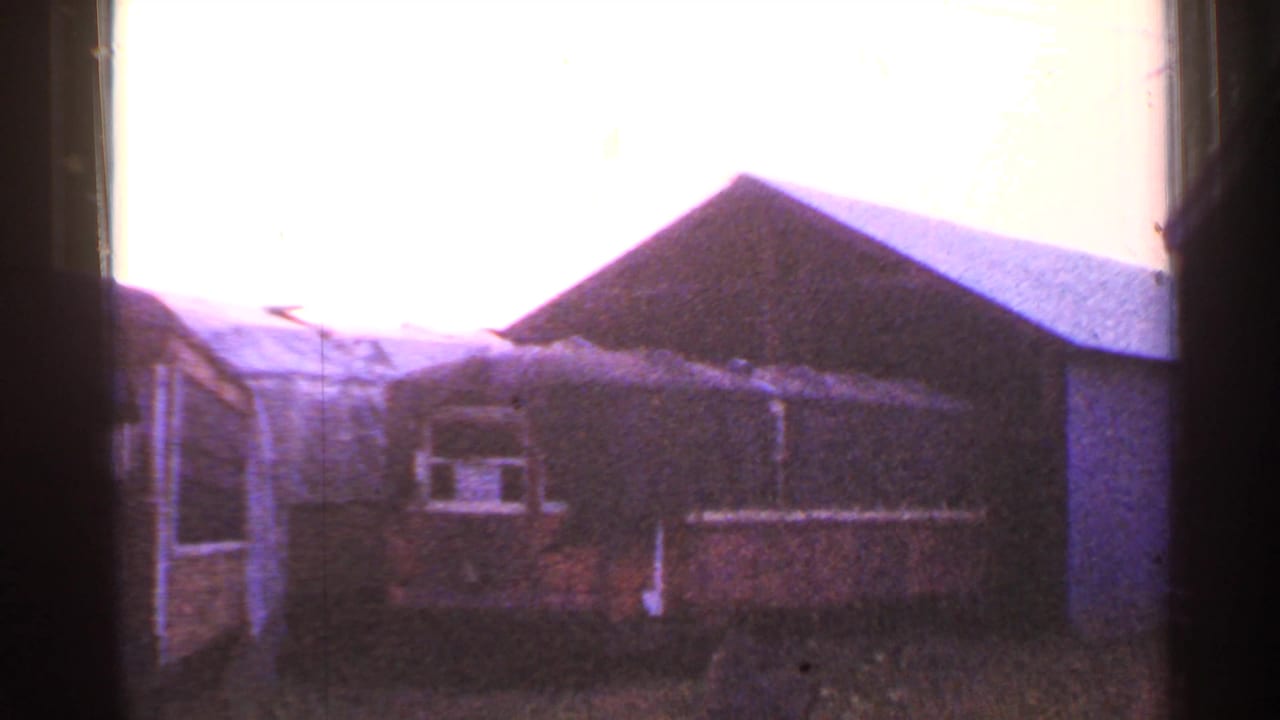 Connecticut home-movie frame from the supplied 1953 clip showing railcars and low yard buildings under bright exposure.