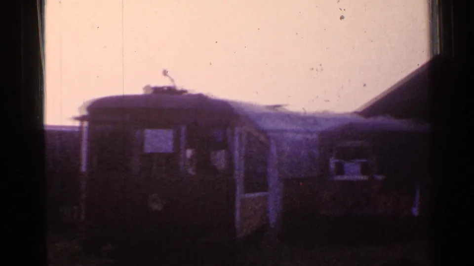 1953 Connecticut 8mm view of a dark passenger railcar with an open-looking doorway and nearby shed-like structure.