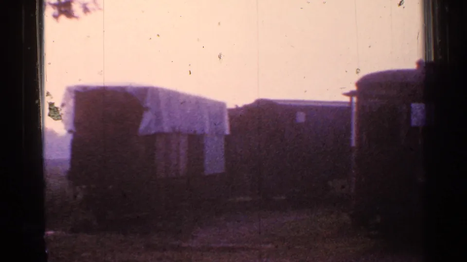 Final 1953 Connecticut frame showing weathered railcar ends in a yard, one with a light draped or covered surface.
