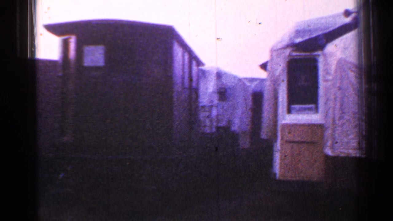 Trailer-like structures and a lighter fabric-covered shelter at right.