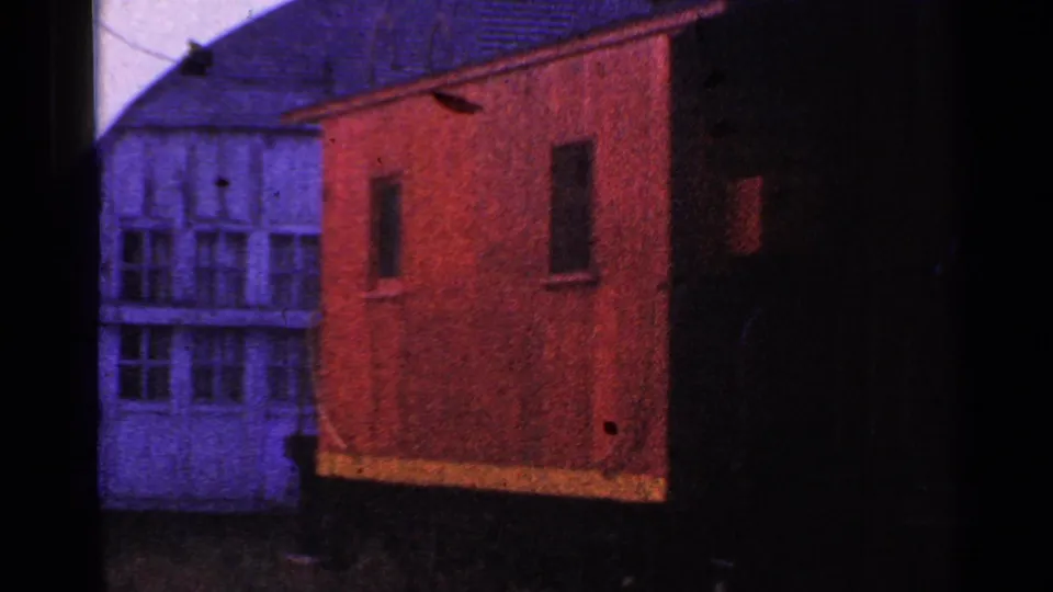 1953 Connecticut 8mm frame showing a red-orange wooden shelter near a pale windowed building.