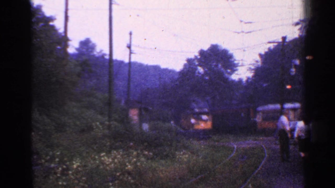 1953 Connecticut 8mm frame showing a train nearing a small rural station as passengers stand near the platform edge.