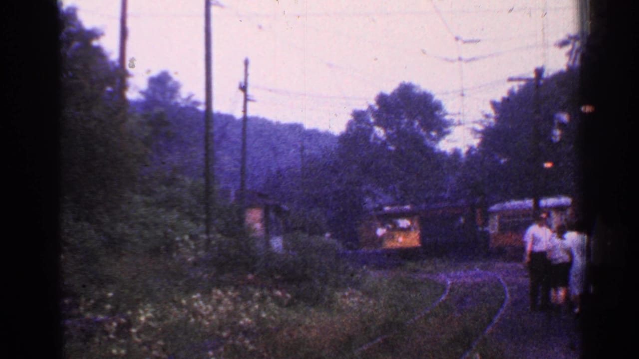 The train is closer to the platform, with several passengers standing at the right edge.