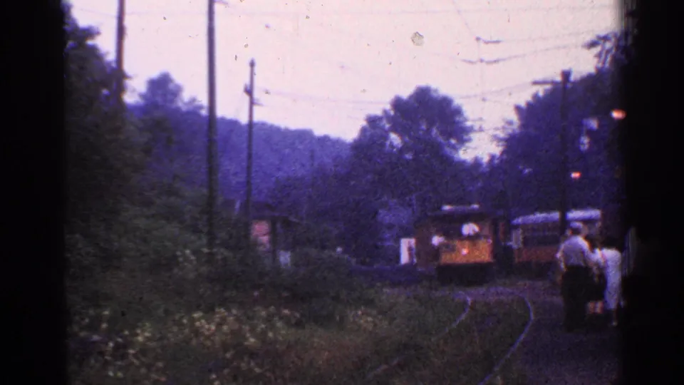 The train advances toward the rural Connecticut platform, with waiting passengers visible in soft 8mm color.