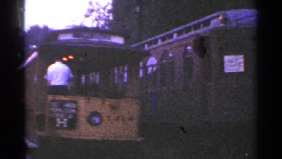 1953 Connecticut 8mm frame showing a person at the front of an open-sided trolley with arched windows beside a wooded area.