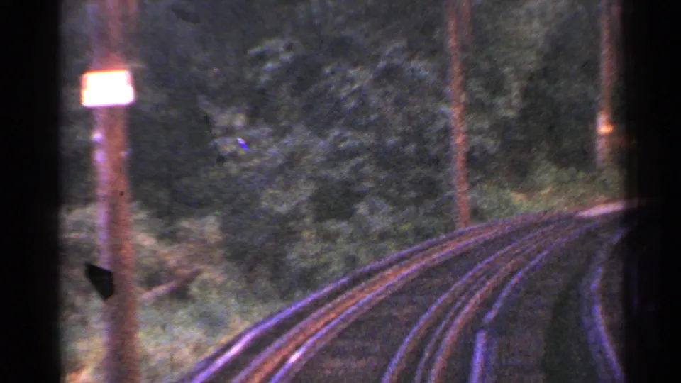End frame of 1953 Connecticut trolley tracks curving through trees, with poles and vegetation visible in grainy 8mm footage.