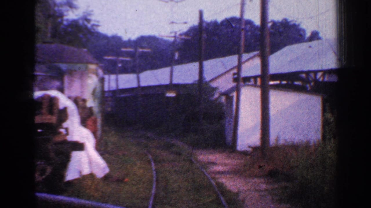 The final frame shows a blurred adult figure near the left foreground as the train passes curved track, light-colored buildings, utility poles, and wooded vegetation in Connecticut.