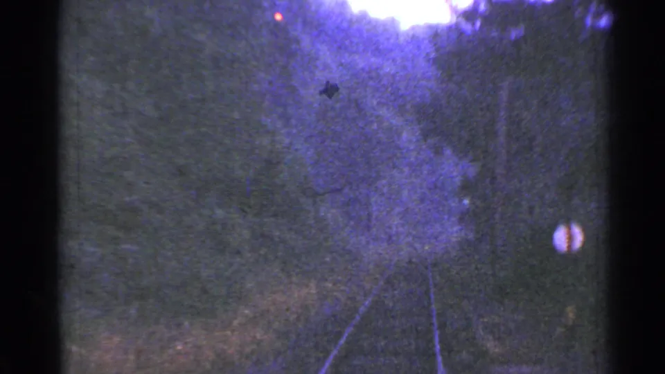 1953 Connecticut rail-travel frame showing tracks receding through trees and hills, with a round trackside sign and soft purple 8mm color.