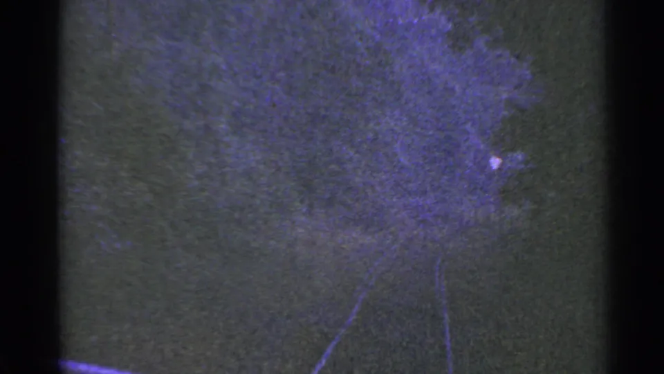 1953 Connecticut 8mm frame showing a dark textured surface with faint track-like lines, purple color shift, and visible film edges.