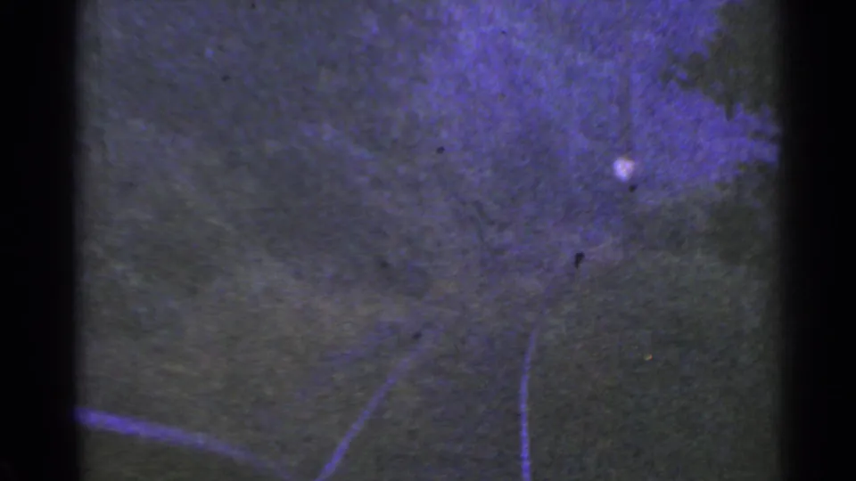 1953 Connecticut home-movie frame with a dark textured surface, faint curving lines, purple-tinted exposure, and film gate edges.